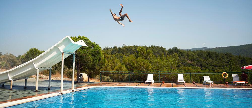 Ein Mann springt in einem Freibad von der Rutsche.