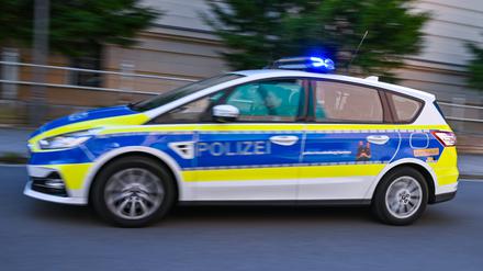Ein Polizeifahrzeug fährt mit Blaulicht auf einer Straße (Symbolbild)