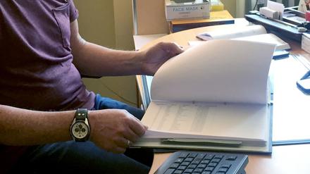 Ein Mitarbeiter des Gesundheitsamts sitzt an seinem Schreibtisch und blättert in Akten. Bis Ende 2022 sollen alle Verwaltungsakte bundesweit online ermöglicht werden.