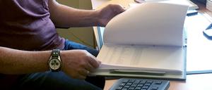 Ein Mitarbeiter des Gesundheitsamts sitzt an seinem Schreibtisch und blättert in Akten. Bis Ende 2022 sollen alle Verwaltungsakte bundesweit online ermöglicht werden.