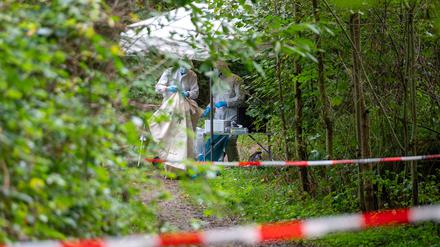 Mitarbeiter der Spurensicherung stehen auf einem abgesperrten Waldweg.
