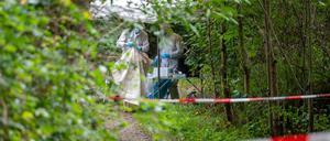 Mitarbeiter der Spurensicherung stehen auf einem abgesperrten Waldweg.