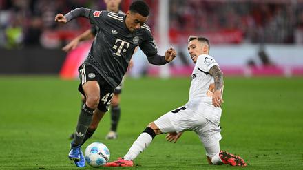 Bayern-Profi Jamal Musiala (links) dribbelt an Leverkusens Alejandro Grimaldo vorbei.