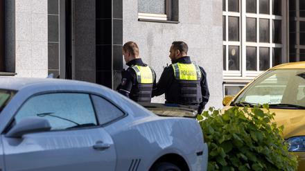 Zwei Polizeibeamte stehen vor dem Eingang des Gebäudes. Bei mehreren Bränden sind 31 Menschen verletzt worden - zwei Kinder schweben in Lebensgefahr.