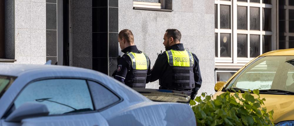 Zwei Polizeibeamte stehen vor dem Eingang des Gebäudes. Bei mehreren Bränden sind 31 Menschen verletzt worden - zwei Kinder schweben in Lebensgefahr.