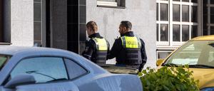 Zwei Polizeibeamte stehen vor dem Eingang des Gebäudes. Bei mehreren Bränden sind 31 Menschen verletzt worden - zwei Kinder schweben in Lebensgefahr.
