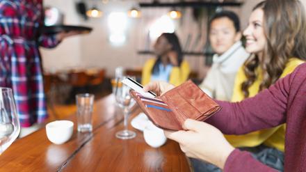 Eine Gruppe junger Menschen beim Bezahlvorgang im Restaurant.
