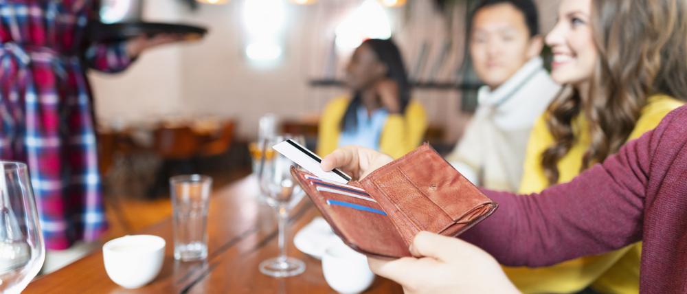 Eine Gruppe junger Menschen beim Bezahlvorgang im Restaurant.