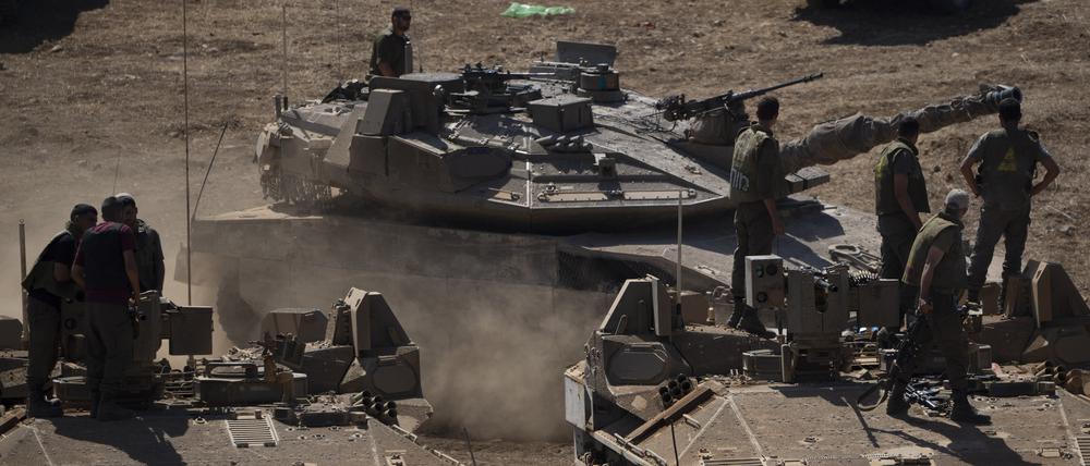 Ein israelischer Panzer fährt im Norden Israels neben Soldaten, die auf einem gepanzerten Mannschaftstransportwagen (APC) stehen. 