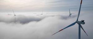 Die Windräder in einem Windpark westlich von Halle ragen aus dem Morgennebel hervor.