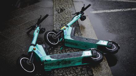 Zwei E-Scooter liegen auf der Straße im Regen.