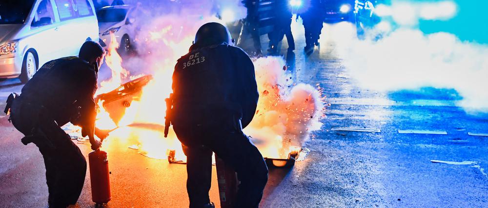 Polizeibeamte versuchen auf der Sonnenallee in Berlin-Neukölln zwei in Brand gesetzte Mülltonnen zu löschen. In der Sonnenallee kam es zu teilweise gewalttätigen Auseinandersetzungen von Menschen, die „Freiheit für Palästina“ skandierten. (Archivbild)