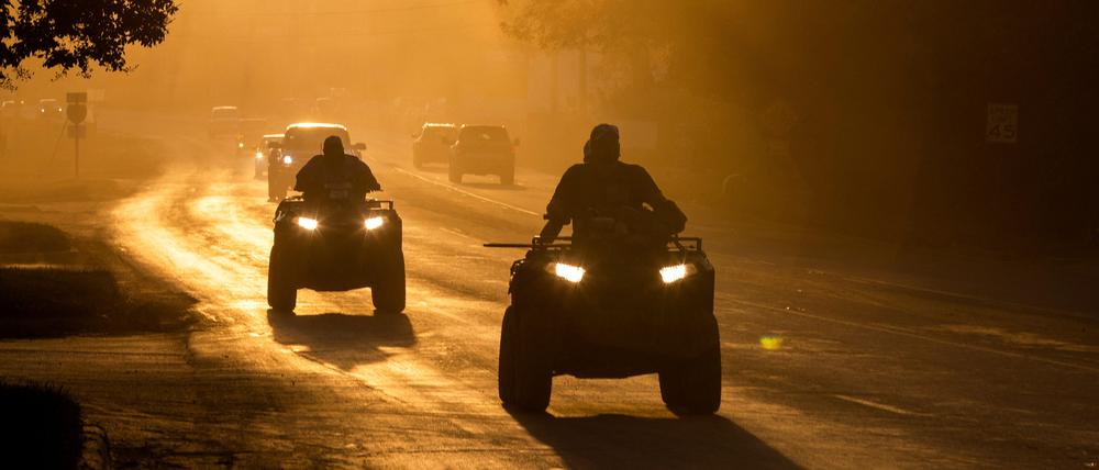 Menschen fahren mit ihrem ATV eine staubige Straße entlang, nachdem der Hurrikan Helene vorbeigezogen ist (Swannanoa, North Carolina, 3. Oktober 2024).