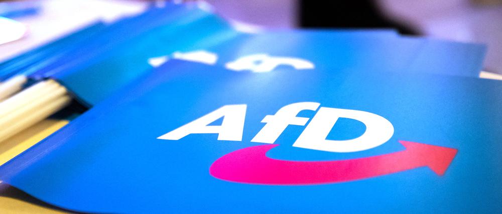Fähnchen mit dem Logo der AfD liegen auf einem Tisch. 