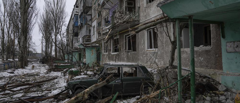 Ein zerstörtes Auto steht vor einem Wohnhaus, das von den russischen Streitkräften schwer bombardiert wurde.