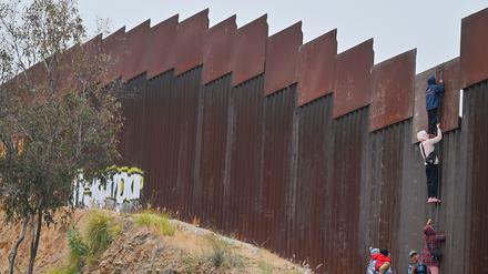 Migranten versuchen aus Mexiko über die Grenzmauer in die USA zu gelangen. 