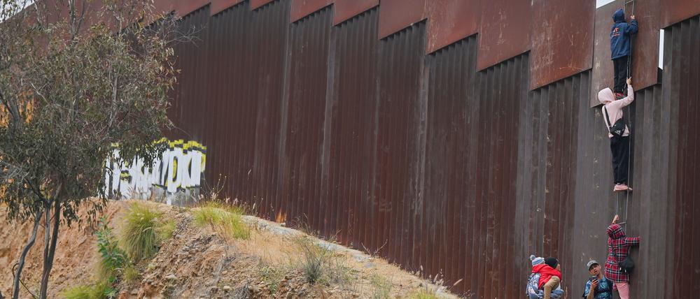Migranten versuchen aus Mexiko über die Grenzmauer in die USA zu gelangen.