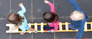 ARCHIV - 20.08.2021, Sachsen, Dresden: Kinder balancieren während eines Pressetermins auf dem Spielplatz einer Kita auf einem Brett. (zu dpa: «Kommission für Teilhabe von Kindern startet») Foto: Sebastian Kahnert/dpa-Zentralbild/dpa +++ dpa-Bildfunk +++