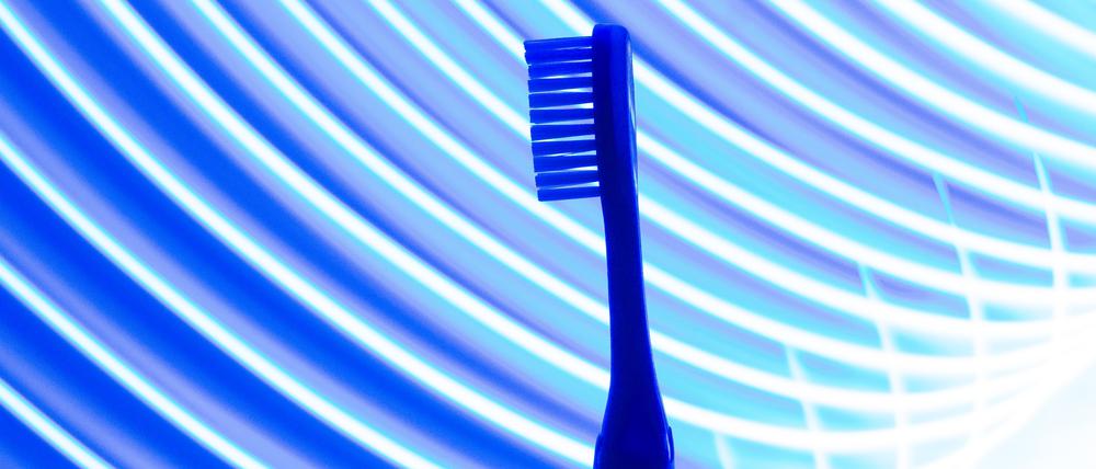 Eine Zahnbürste vor einem neon-blauen Hintergrund.