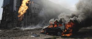 Nach zwei russischen Bombenanschlägen brennt ein Auto in Charkiw vor einem Geschäftszentrum, das durch die Angriffe beschädigt wurde.