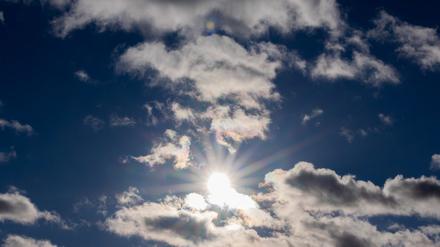 Die Sonne scheint zwischen Wolken hindurch. (Symbolbild)