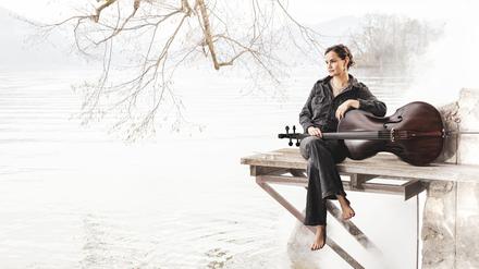 Die Cellistin Raphaela Gromes sitzt mit ihrem Instrument an einem See auf einem Steg.
