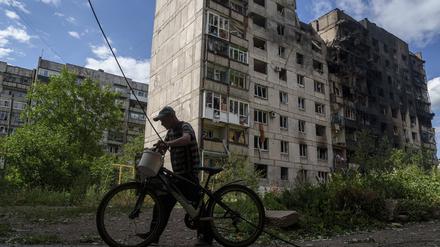 Ein Mann schiebt sein Fahrrad vor einem Wohnhaus in Torezk, das durch einen russischen Luftangriff zerstört wurde (Archivfoto).