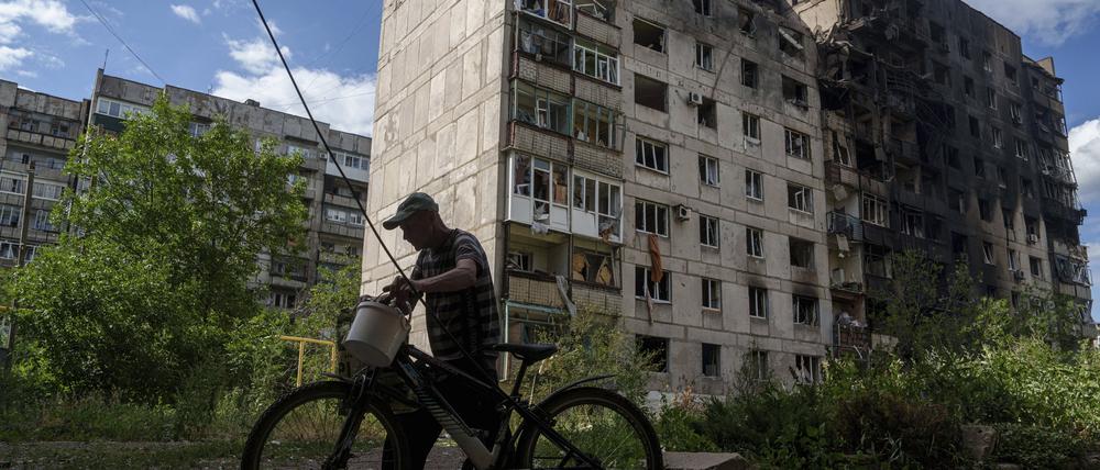 Ein Mann schiebt sein Fahrrad vor einem Wohnhaus in Torezk, das durch einen russischen Luftangriff zerstört wurde (Archivfoto).