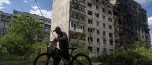 Ein Mann schiebt sein Fahrrad vor einem Wohnhaus in Torezk, das durch einen russischen Luftangriff zerstört wurde (Archivfoto).