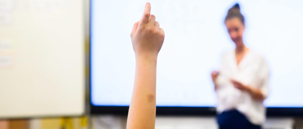Ein Schüler in einem Klassenraum in Hannover meldet sich per Handzeichen.