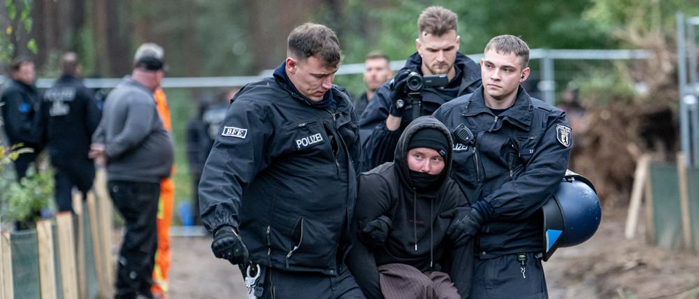 Polizisten nehmen nach einer Besetzung eines Baufahrzeuges Umweltaktivisten im Wald am Tesla Werk fest.