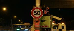 Bauarbeiter montieren an der Porte d’Ivry in Paris ein Schild mit einem Tempolimit von 50 km/h auf der Pariser Ringstraße, dem Boulevard Périphérique. 