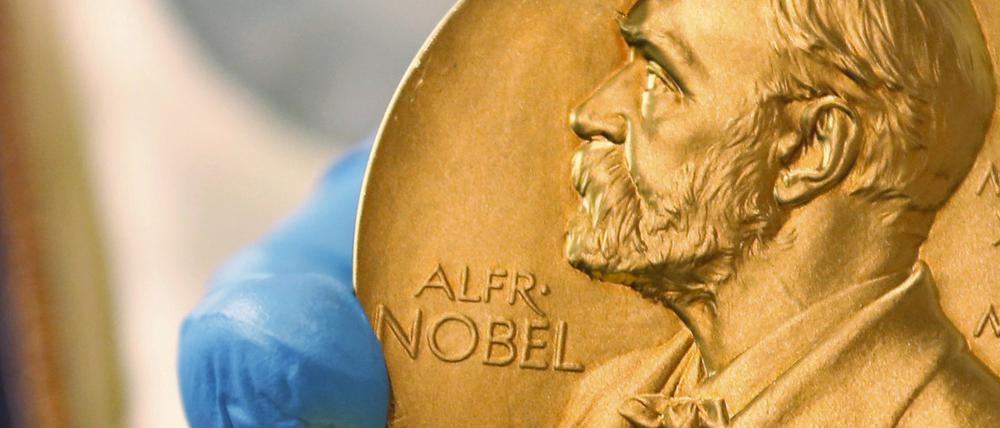 Ein Mitarbeiter der Nationalbibliothek zeigt eine goldene Nobelpreismedaille. 