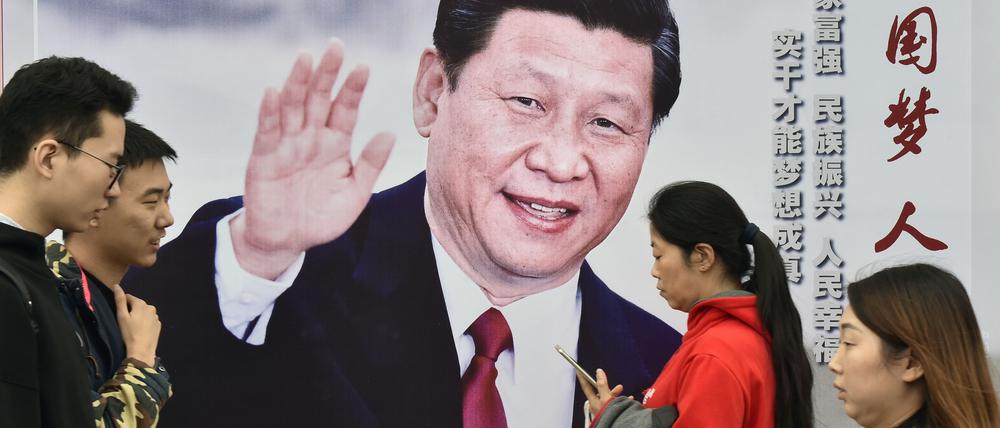 Passanten gehen am 17.10.2017 in Peking (China) an einem Plakat vorbei, das den chinesischen Präsidenten Xi Jinping zeigt.