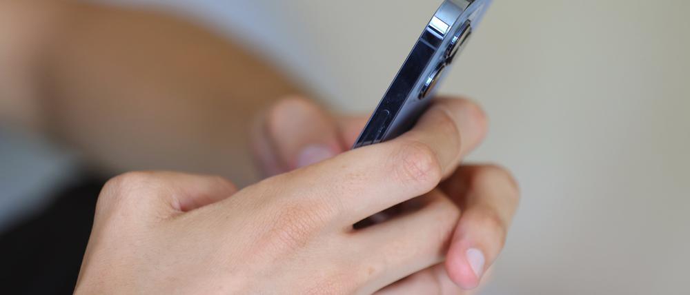 Ein Jugendlicher hält ein Smartphone in den Händen. 