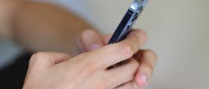 Ein Jugendlicher hält ein Smartphone in den Händen. 