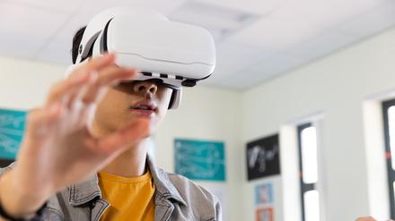 Ein junger Mann trägt eine Virtual-Reality-Brille und streckt die Arme vor sich.