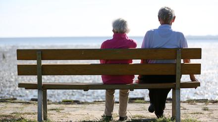 Ein Senioren-Paar sitzt auf einer Bank und schaut auf das im Watt vor Dagebüll (Schleswig-Holstein). 