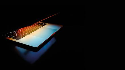 Halb aufeklappter Laptop vor dunklem Hintergrund. Betrüger gehen immer raffinierter vor. Geraten Konto-Zugangsdaten einmal in die falschen Hände, kann das Geld schnell weg sein.