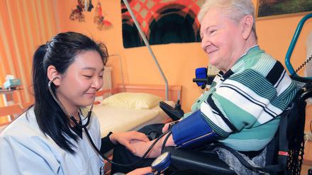 Mulin Lin, Pflegeassistentin aus China, misst am 10.03.2015 den Blutdruck der Rentnerin Margot Krüger im Seniorenzentrum der Arbeiterwohlfahrt in Magdeburg.
