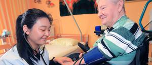 Mulin Lin, Pflegeassistentin aus China, misst am 10.03.2015 den Blutdruck der Rentnerin Margot Krüger im Seniorenzentrum der Arbeiterwohlfahrt in Magdeburg.