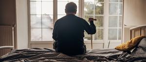 Allein im Heim: Ein Mann sitzt auf seinem Bett.