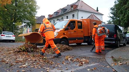 Mitarbeiter der Berliner Stadtreinigung befreien eine Straße vom Herbstlaub. 