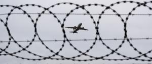 Ein Flugzeug startet am Flughafen Hannover, fotografiert durch Stacheldraht am Flughafenzaun.