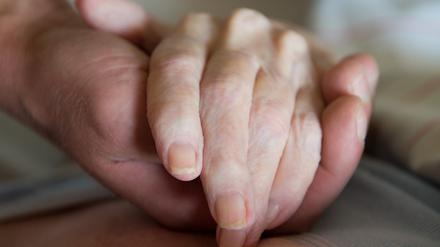 Ein Altenpfleger hält in einem Pflegeheim die Hand einer Frau. (Symbolbild)