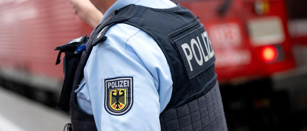 Bayern, München: Ein Bundespolizist steht am Hauptbahnhof an einem Bahnsteig vor einem Zug der Deutschen Bahn.