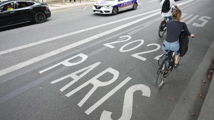 Frankreich, Paris: Vor den Olympischen Sommerspielen, Olympia Paris 2024, Fahrradfahrer fahren auf einer Busspur für Paris 2024 an einem Polizeifahrzeug vorbei. Ein SUV-Fahrer steht in Paris unter Verdacht, einen Radfahrer nach einem Verkehrsstreit absichtlich überfahren und getötet zu haben.