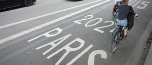 Frankreich, Paris: Vor den Olympischen Sommerspielen, Olympia Paris 2024, Fahrradfahrer fahren auf einer Busspur für Paris 2024 an einem Polizeifahrzeug vorbei. Ein SUV-Fahrer steht in Paris unter Verdacht, einen Radfahrer nach einem Verkehrsstreit absichtlich überfahren und getötet zu haben.