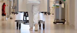 Eine Krankenpflegerin schiebt ein Krankenbett durch einen Krankenhausflur. 