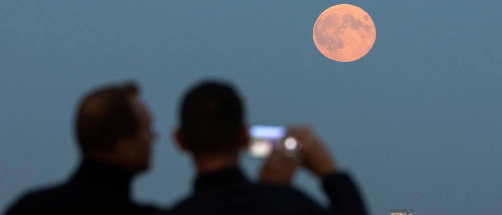 Menschen fotografieren den aufgehenden Supermond, auch bekannt als Jägermond, in Berlin, Deutschland, am 17. Oktober 2024.